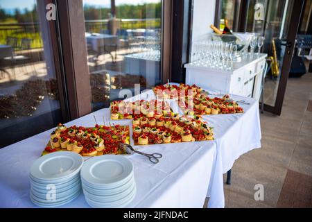 Verschiedene Kanapees mit geräuchertem Lachs, Gurkenskirschtomaten und Mozzarella werden auf einem Tisch serviert. Hochwertige Fotos Stockfoto