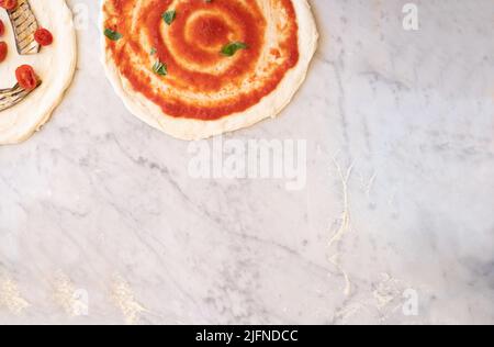 Hintergrundbild von einigen Pizzen auf Marmorplatte mit Mehl und traditionellen italienischen Zutaten, traditionelle neapolitanische Pizza Stockfoto