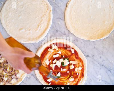 Hintergrundbild von einigen Pizzen auf Marmorplatte mit Mehl und traditionellen italienischen Zutaten, traditionelle neapolitanische Pizza Stockfoto