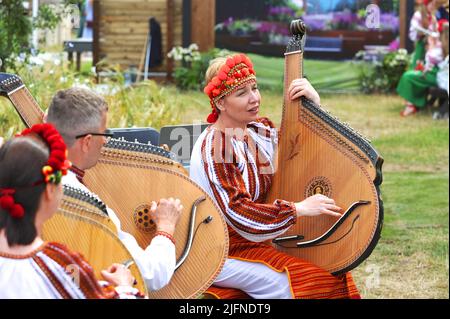 Hampton Court Palace, Surrey, Großbritannien - 04.06.2022, ukrainische Musiker spielen traditionelle Musik im What does Not Burn Garden. Das verwendete Instrument ist eine Bandura oder Kobza (auch bekannt als die "ukrainische Harfe"). Der Garten, der im RHS Hampton Court Palace mit dem Best Global Impact Garden Award ausgezeichnet wurde, ist eine Destillation der ukrainischen Landschaft und Kultur. Es zeigt den Rushnyk, ein besticktes Tuch, das in vielen Ritualen verwendet wird, als Symbol des Lebens und der Identität. Die seit 1993 stattfindende Messe ist die prestigeträchtigste Blumen- und Gartenveranstaltung im Vereinigten Königreich und die größte jährliche Blume der Welt Stockfoto