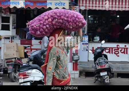 Beawar, Rajasthan, Indien, 4. Juli 2022: Eine ländliche Frau trägt in der Regenzeit einen mit Zwiebeln gefüllten Sack auf einem Markt in Beawar. Kredit: Sumit-Samarwat/Alamy Live Nachrichten Stockfoto