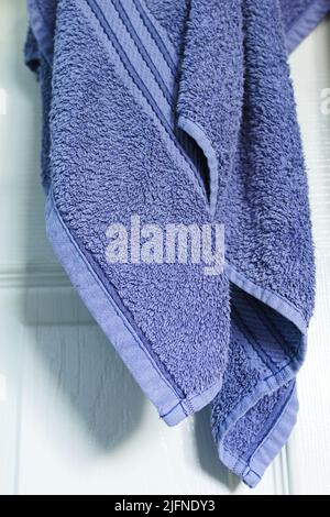 Blaues Handtuch hängt an einer weißen Tür Stockfoto