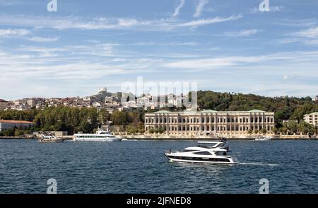 Blick auf eine Yacht, die am historischen Palast auf dem Bosporus und der europäischen Seite Istanbuls vorbeifährt. Es ist ein sonniger Sommertag. Wunderschöne Szene. Stockfoto