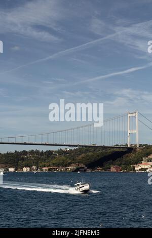 Blick auf eine Yacht, die auf der Bosporus- und FSM-Brücke in Istanbul vorbeifährt. Es ist ein sonniger Sommertag. Wunderschöne Reiseszene. Stockfoto