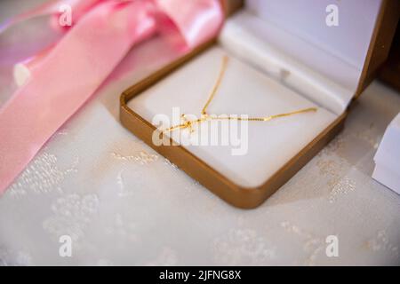 Ein kleines goldenes Kreuz in einer Schmuckschatulle, das für die Taufe eines Babys vorbereitet wurde. Hochwertige Fotos Stockfoto