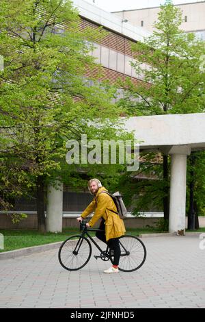Porträt eines jungen Mannes mit Rucksack, der sein Fahrrad für den Transport in der Stadt benutzt Stockfoto