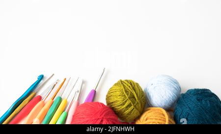 Bunte Wollkugeln und farbige Häkelnadeln, isoliert auf weißem Hintergrund. Garn zum Stricken. Garnknäuel. Platz zum Kopieren, Draufsicht, flach liegend. Stockfoto