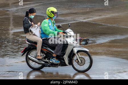 SAMUT PRAKAN, THAILAND, MÄRZ 28 2022, Ein Motorrad-Taxifahrer mit Fahrgästen fährt im Regen Stockfoto