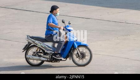 SAMUT PRAKAN, THAILAND, APR 15 2022, Ein Mann mit Gesichtsmaske fährt ein Motorrad auf der Straße Stockfoto