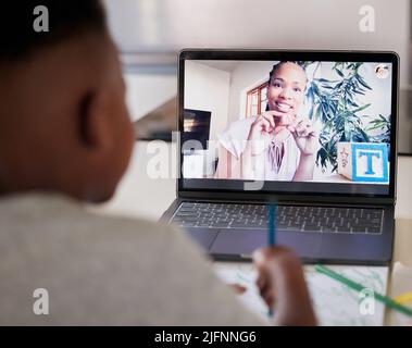 Fernunterricht mit Zoom. afroamerikanische Lehrerin auf einem Laptop-Bildschirm nach Hause schulte einen jungen Jungen aus der Ferne. Schwarze Tutorin, die eine Lektion erteilt Stockfoto