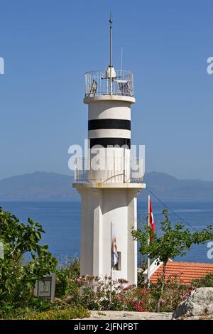 Kusadasi, Türkei - Juni Mai 2022: Besucher, die am historischen Leuchtturm auf Pigeon Island im Hafen von Kusadasi vorbeilaufen. Stockfoto