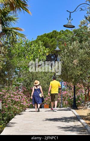 Kusadasi, Türkei - Juni 2022: Besucher, die am Leuchtturm auf der Pigeon Island im Hafen von Kusadasi vorbeilaufen. Stockfoto