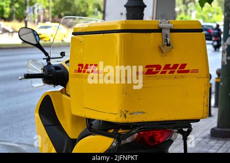 Athen, Griechenland - 2022. Juni: Container auf der Rückseite eines Motorrollers eines Kuriers mit dem DHL-Logo. Stockfoto