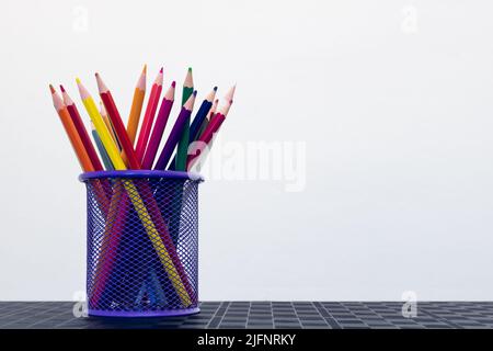 Buntstifte in einem Bleistifthalter auf dem Schreibtisch isoliert auf weißem Hintergrund. Leerer Raum für Text Stockfoto