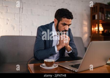 Beschäftigter junger Geschäftsmann, der Kaffee trinken und seine Arbeit erledigen kann. Stockfoto