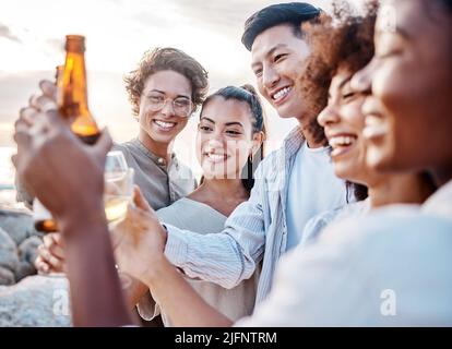 Eine Gruppe von Freunden genießt ihre Zeit zusammen und feiert mit einigen alkoholischen Getränken am Strand Stockfoto