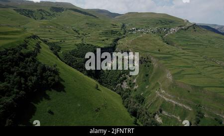 Luftaufnahme eines riesigen schönen Felsens mit Wolken im Hintergrund. Aktion. Fliegen über Berge mit grünen Hängen. Stockfoto