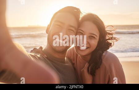 Porträt eines jungen, vielfältigen Birazialpaares, das am Strand ein Selfie macht und sich draußen amüsieren kann. Porträt eines jungen, vielfältigen Birazialpaares, das ein Stockfoto