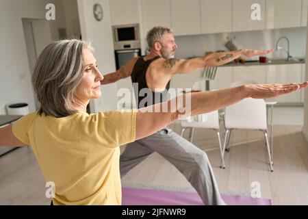 Fit mittleren Alters Familienpaar dabei Krieger Yoga-Übung zu Hause. Stockfoto