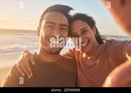 Porträt eines jungen, vielfältigen Birazialpaares, das am Strand ein Selfie macht und sich draußen amüsieren kann. Porträt eines jungen, vielfältigen Birazialpaares, das ein Stockfoto