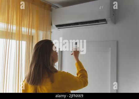 Frau mit Fernbedienung für die Klimaanlage. Stockfoto