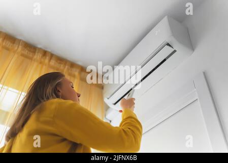 Frau mit Fernbedienung für die Klimaanlage. Stockfoto