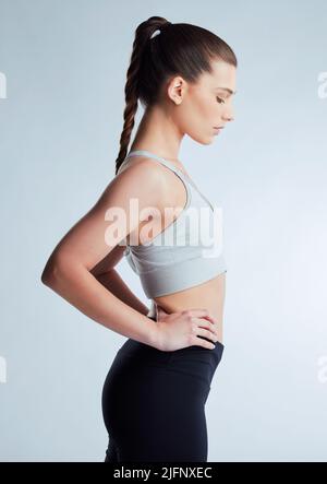 Shes bereit für ihr Workout. Beschnittene Aufnahme einer attraktiven jungen Sportlerin, die im Studio vor grauem Hintergrund posiert. Stockfoto