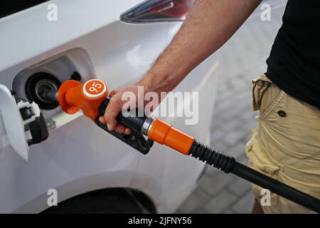 Die Hand des Mannes hält eine Füllpistole, die an einer Tankstelle in das Tankloch eines Autos eingeführt wurde. Nahaufnahme einer Hand und einer Tankpistole. Das Konzept von Th Stockfoto