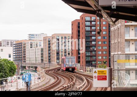 DLR Docklands Light Railway am Bahnhof West Silvertown in London. Der DLR-Zug kommt an einem hellen Tag am Bahnhof an Stockfoto