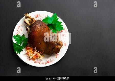 Gebratene Schweinshaxe. Schinken und Speck sind im Westen beliebte Gerichte. Geräucherter Schinken mit Kräutern und Gewürzen. Schwarz isoliert .Deutsch Haxe oder Schweinshaxe. Stockfoto