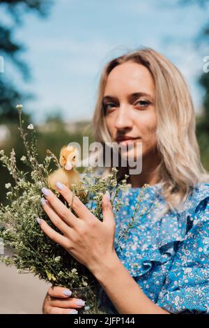 Schönes Mädchen mit Wildblumen und Entchen in ihren Händen Stockfoto