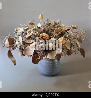 Bouquet von getrockneten Blumen in Keramikvase auf neutralem Hintergrund Stockfoto