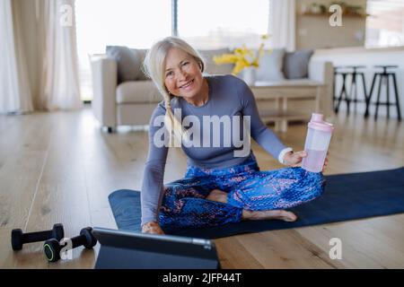 Fit Senior Frau mit Online-Training Klasse zu Hause, aktives Lifestyle-Konzept. Stockfoto