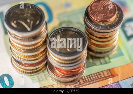 Stapel verschiedener Euro-Münzen auf Euro-Banknoten. Drei Türme von Euro auf 100, 50 und 20 Euro Scheine Stockfoto