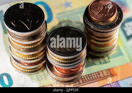 Stapel verschiedener Euro-Münzen auf Euro-Banknoten. Drei Türme von Euro auf 100, 50 und 20 Euro Scheine Stockfoto