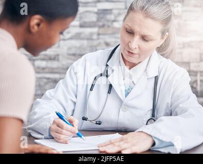 Erläuterung des Verfahrens und der erforderlichen Behandlung. Aufnahme eines Arztes, der während einer Konsultation mit einem Patienten in einer Arztpraxis Papierkram durchläuft. Stockfoto