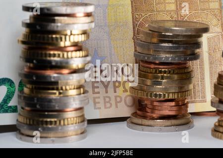 Gestapelte Euro-Münzen vor einer 200-Euro-Banknote. EURO-Schrift auf der Rechnung in gelb Stockfoto