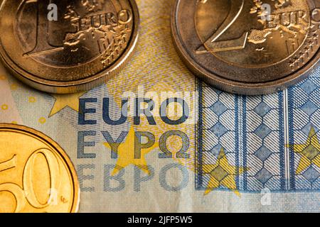 Euro-Banknote mit Münzen. Nahaufnahme des EURO-Schreibens über Geld. 20-Euro-Schein mit zwei und einer Euro-Münze. 50 Cent Münze. Stockfoto