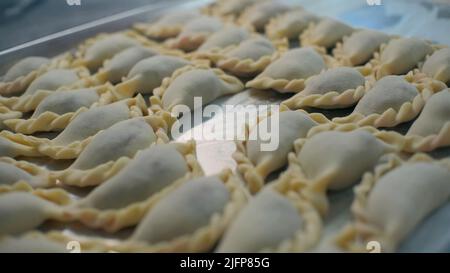 Knödel auf Backblech. Clip. Viele leckere Knödel auf Brettern. Fertigknödel für das Massengaren Stockfoto