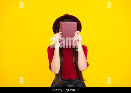 Schulmädchen mit Buch kopieren posiert auf isoliertem Hintergrund. Literaturunterricht, Gymnasium. Intellektueller Kinderleser. Stockfoto