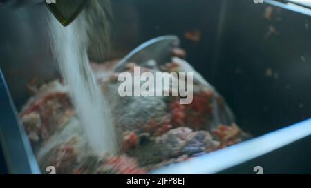 Mischen von Hackfleisch im Produktionsmischer. Clip. Die Mischung mit Hackfleisch wird in großen Mengen in der Produktion geknetet. Lebensmittelproduktion Stockfoto