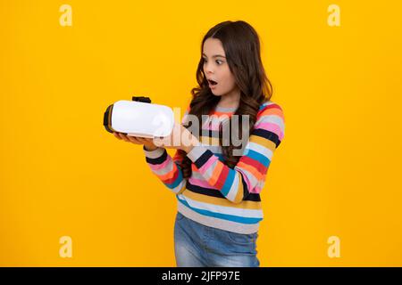 Porträt eines jungen Teenagers in VR-Helm, isoliert auf Gelb. Gamer spielen VR-Spiele, VR-Spiele. Schockiert erstaunt Gesicht, überrascht Emotionen der jungen Stockfoto