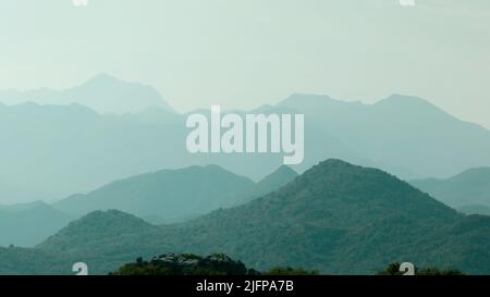 Spektakulärer Morgennebel in den Bergen über seinen Gipfeln. Kreativ. Nebel im grünen Bergwald, Morgennebel und atemberaubende Hügel. Stockfoto