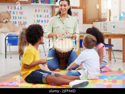 So spielen Sie es. Aufnahme einer Frau, die ihre Klasse über Musikinstrumente unterrichtet. Stockfoto