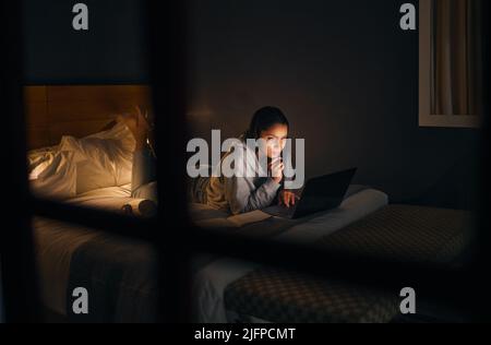 Ein wenig Nachforschung spät in der Nacht. Eine kurze Aufnahme einer attraktiven jungen Frau, die spät in der Nacht in ihrem Schlafzimmer zu Hause studiert. Stockfoto