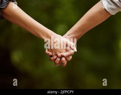 Geh mit mir durch die Wildnis. Nahaufnahme eines unverkennbaren Paares, das Hand in Hand durch die Wildnis geht. Stockfoto