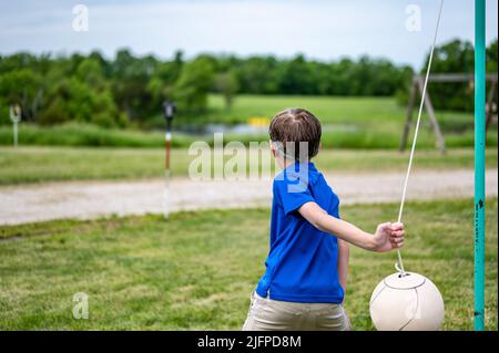 Tetherball wird in einem Spiel mit einem kleinen Jungen getroffen und umgeseilt. Stockfoto