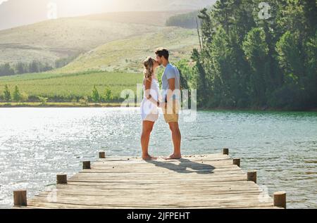 Ich hoffe, dieser Moment dauert ewig. Aufnahme eines jungen Paares, das sich auf einem Steg an einem See festklebte. Stockfoto