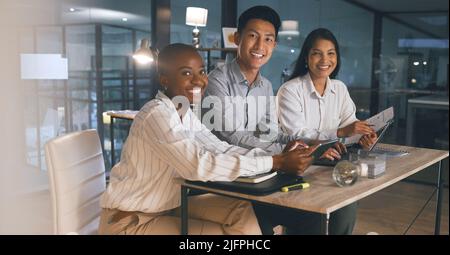 Sieht aus wie eine späte Nacht. Aufnahme einer Gruppe von Geschäftsleuten, die spät in einem modernen Büro arbeiten. Stockfoto