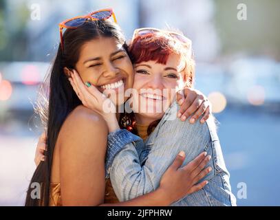 In der Stadt mit meinem Lieblingshotel. Beschnittenes Porträt von zwei attraktiven jungen Freundinnen, die sich umarmen, während sie in der Stadt unterwegs sind. Stockfoto